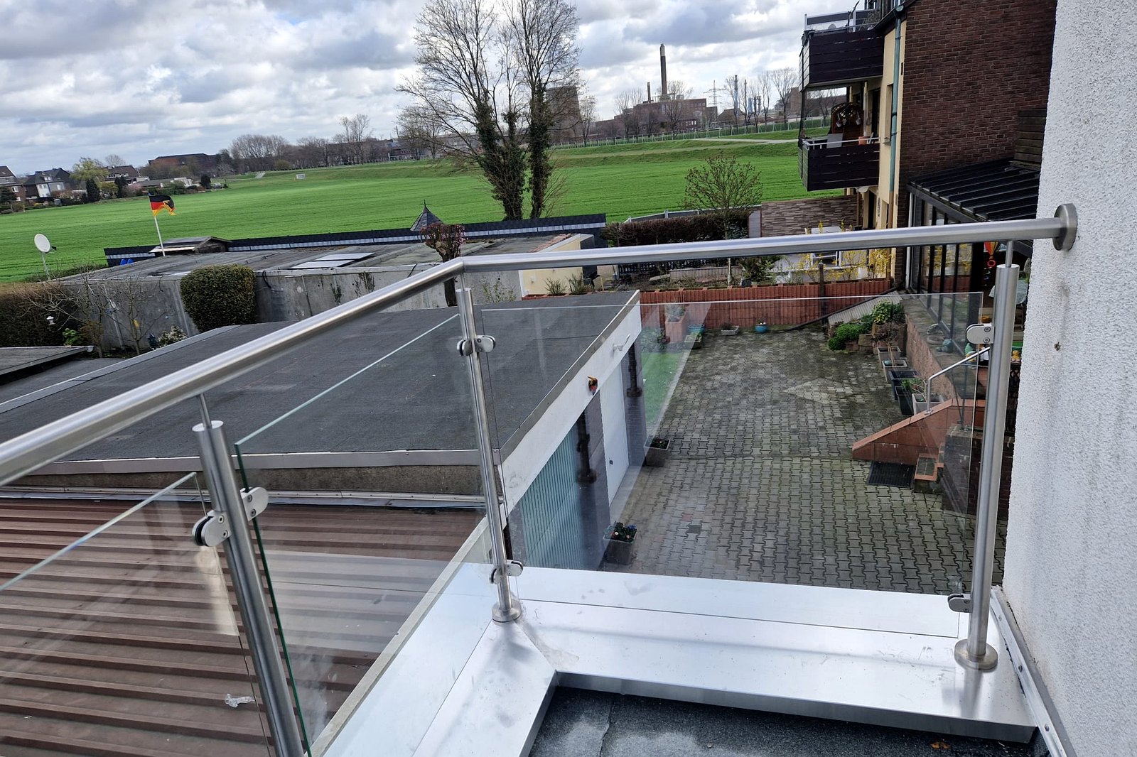 Uitzicht vanaf het balkon over open landschap, met de glazen balustrade op de voorgrond.