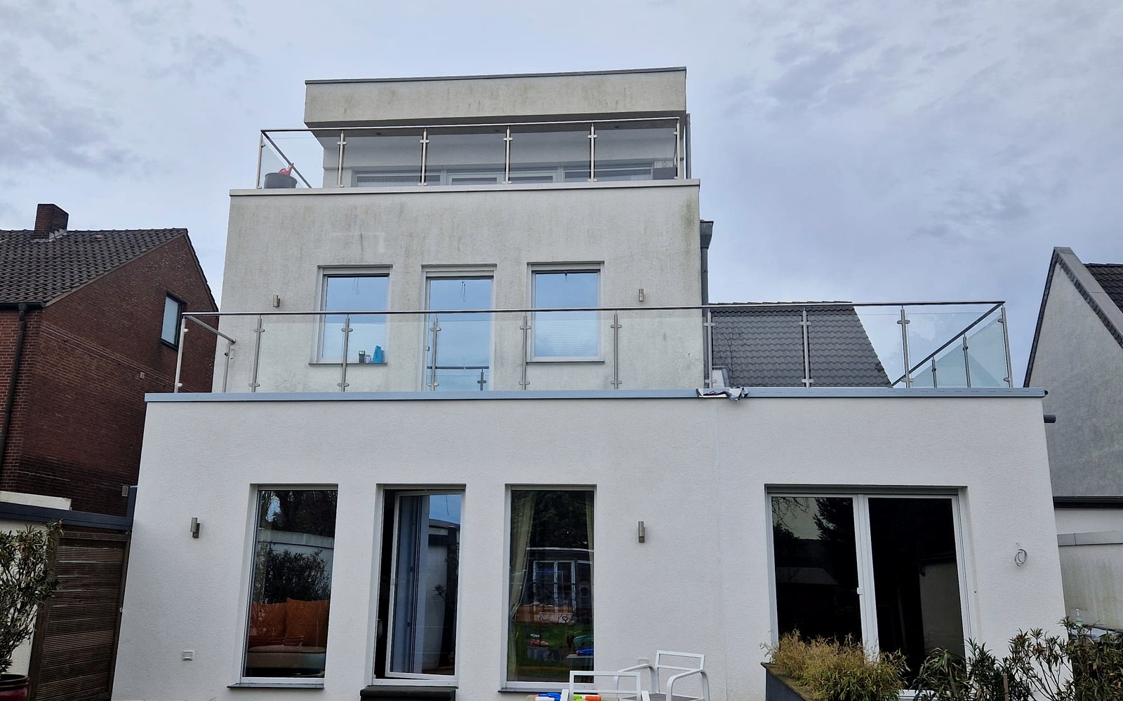 Moderne witte woning met dakopbouw, dakterras en doorlopende glazen balustrades