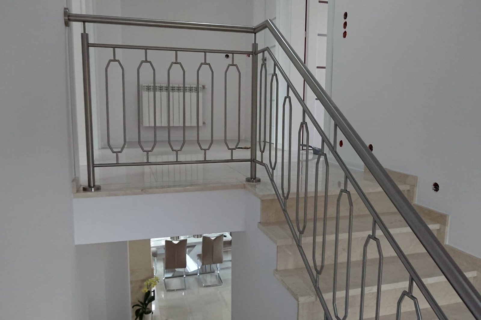 Roestvast stalen trapleuning met spijlen langs het bovenbordes van het trappenhuis.