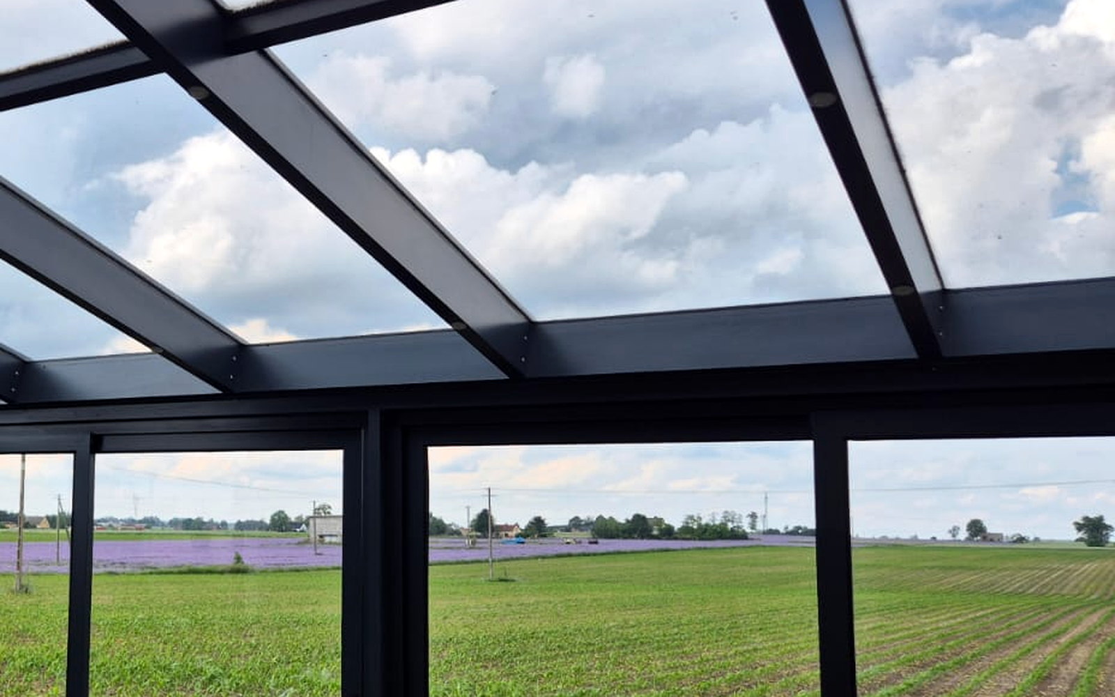 Interieur van een tuinkamer met glasdak en doorlopend zicht over de velden