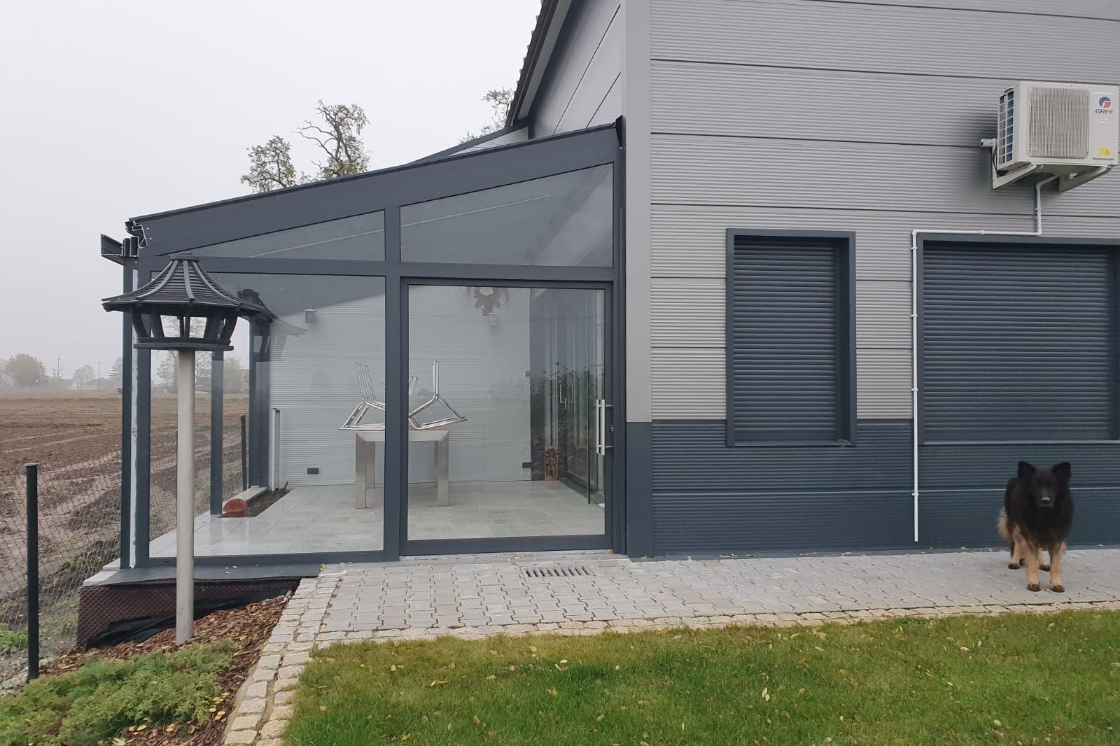 Zijaanzicht van de tuinkamer met terras en gazon.