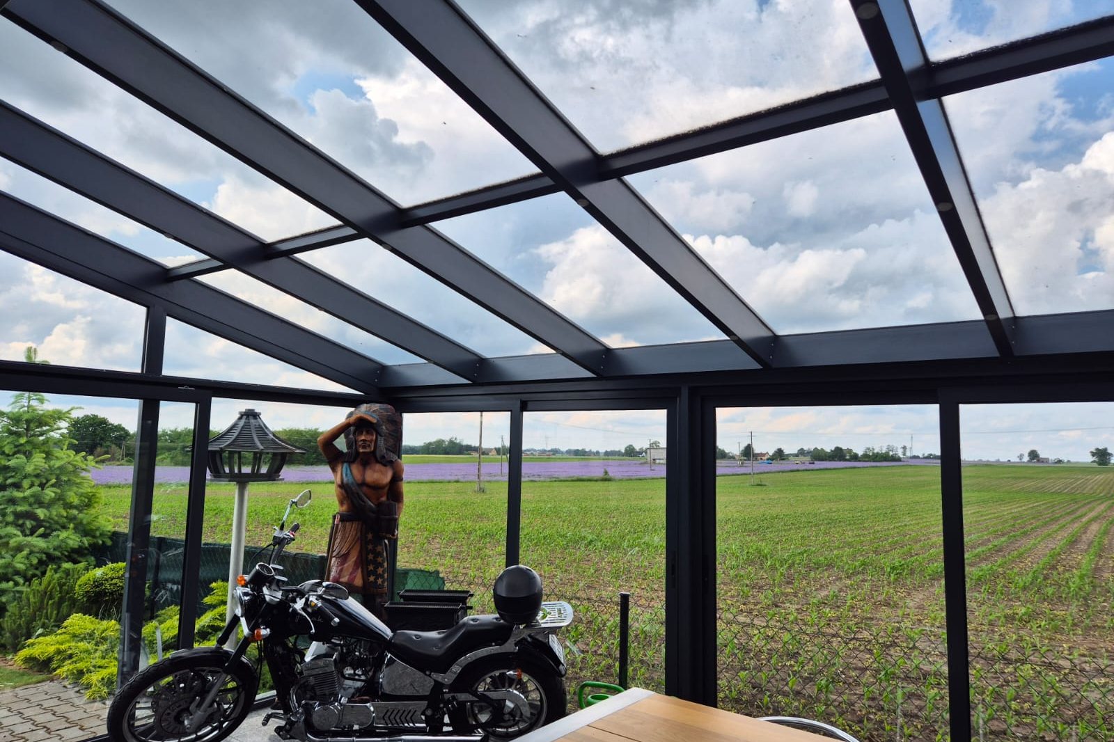 Glazen schuifwanden en glasdak van een overkapping met uitzicht over open land