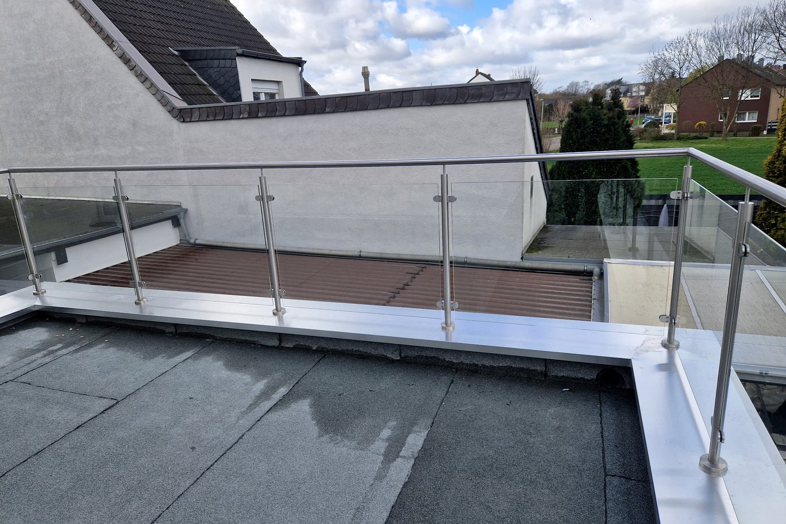 Detail van een glasvulling in een roestvast stalen balustrade langs de rand van het dakterras.