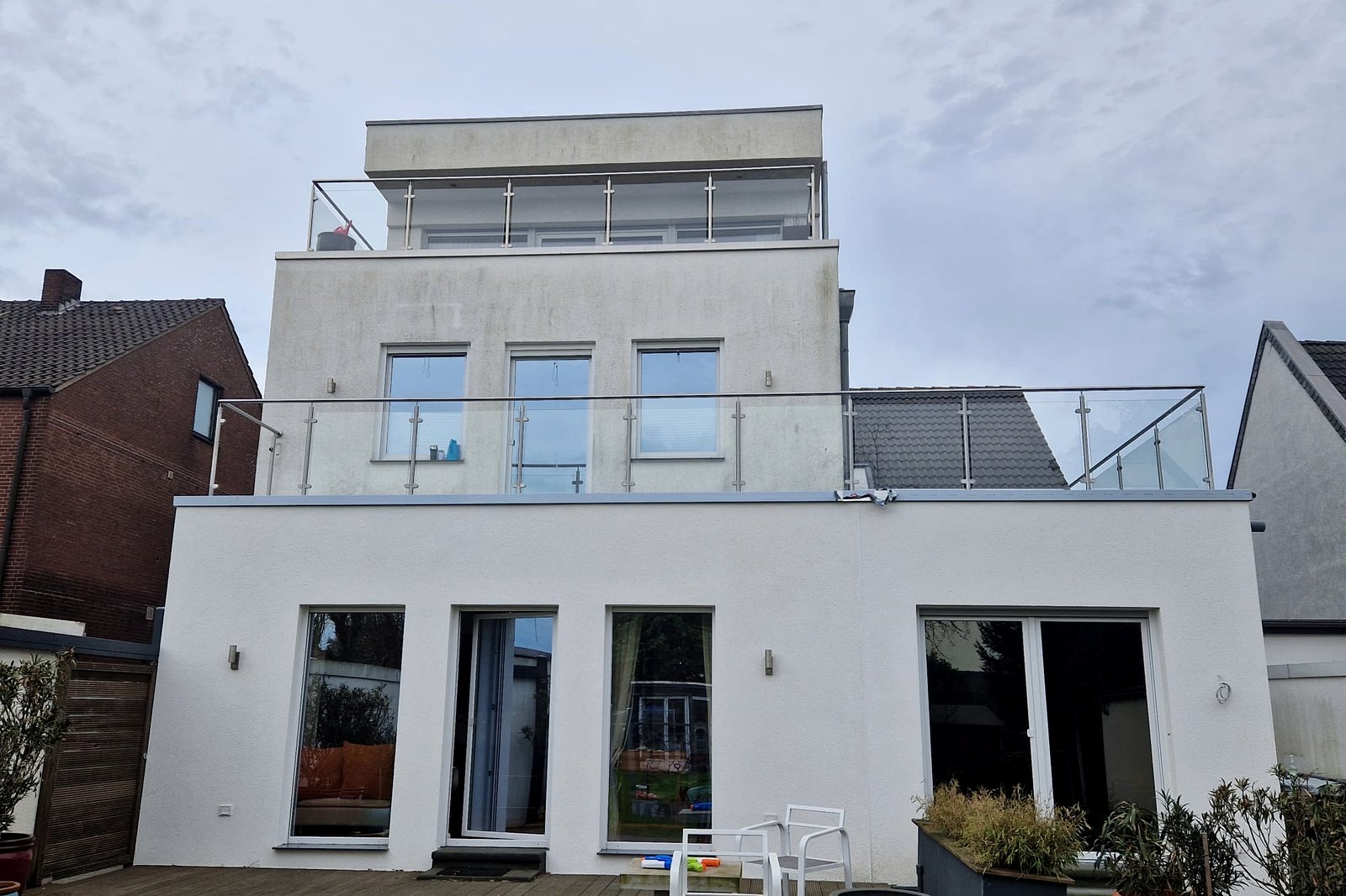Achterzijde van de woning met meerdere balkons met glazen balustrades.