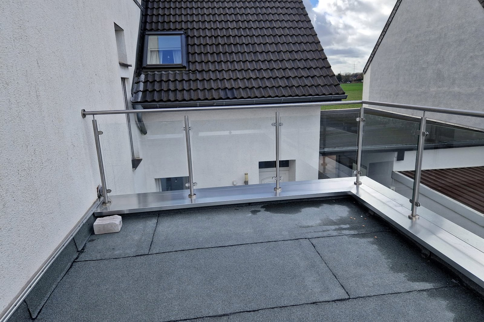 Hoekoplossing van de glazen balustrade met doorlopende stalen handregel.