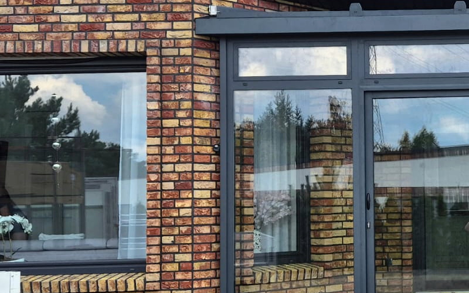 Detail van een antracietgrijs aluminium kozijn met isolerende beglazing in bakstenen metselwerk